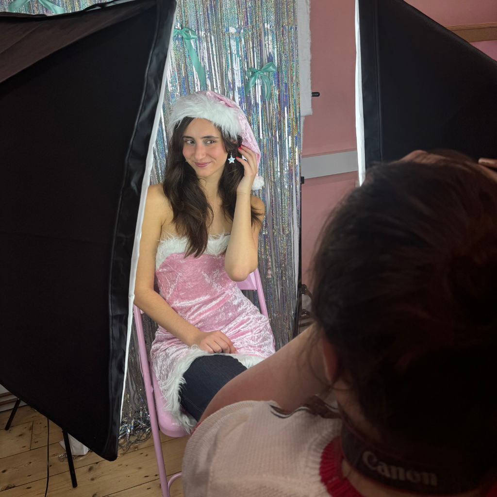 A woman posing for a photoshoot in a pink santa dress