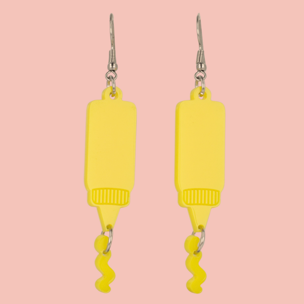 Stainless steel earwires featuring mustard acrylic charms with a charm joined to the bottle showing sauce coming out of it