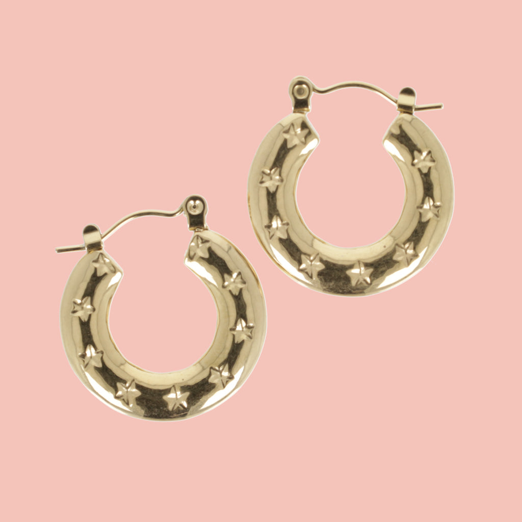 Gold horseshoe-shaped earring with stars surrounding the horsehoe