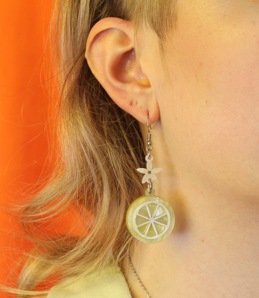 Lemon slice charms suspended fromn white flower charms on stainless steel earwires