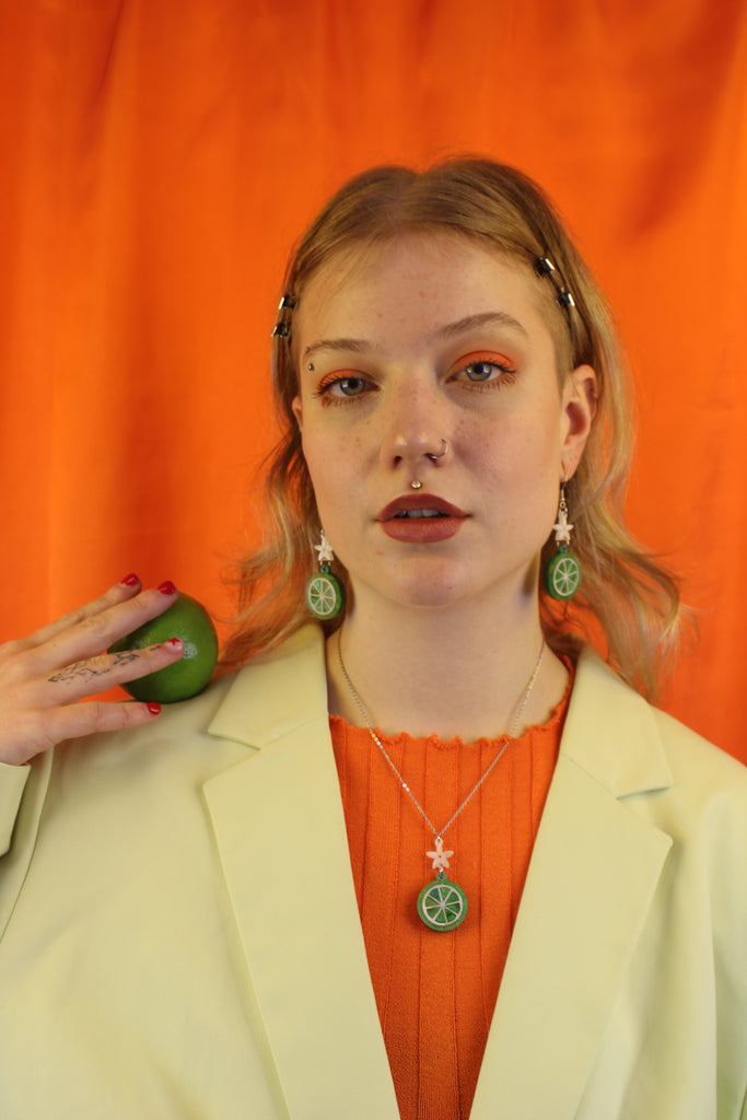 Model wearing Lime slice pendant suspended rom a white flower and stainless steel chain