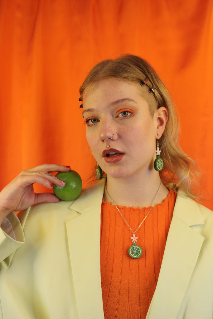 Model wearing Lime slice pendant suspended rom a white flower and stainless steel chain