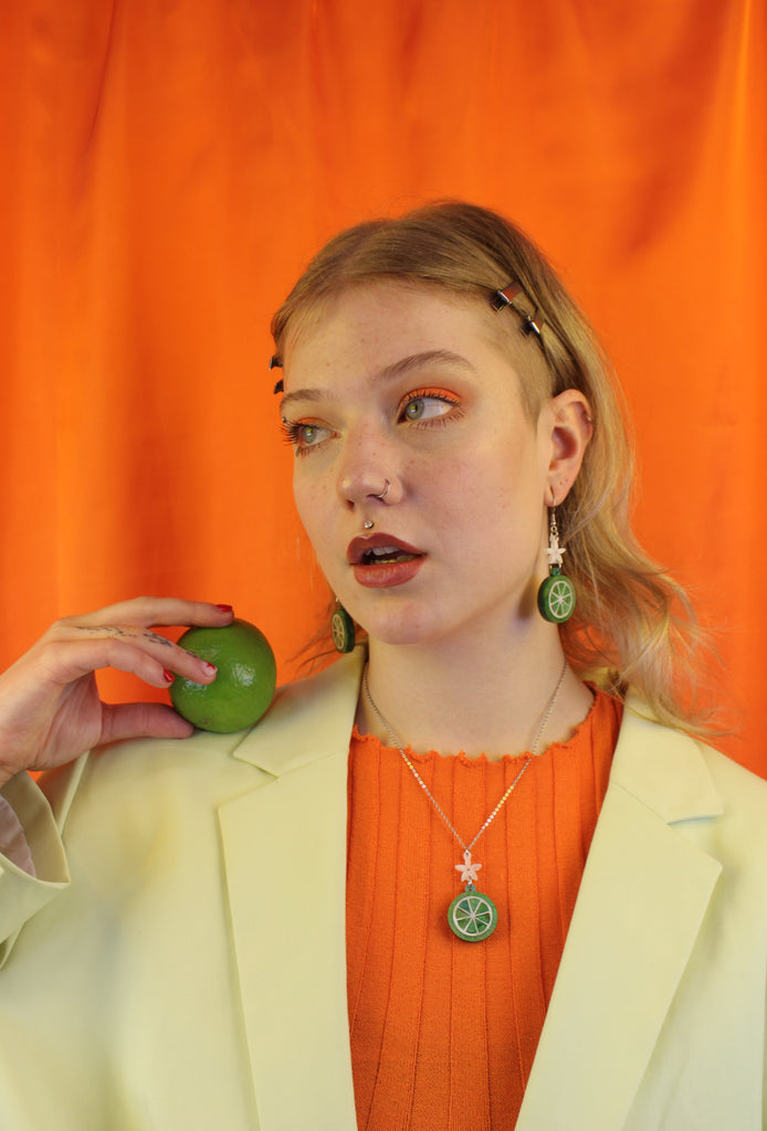 Model wearing Lime slice pendant suspended rom a white flower and stainless steel chain