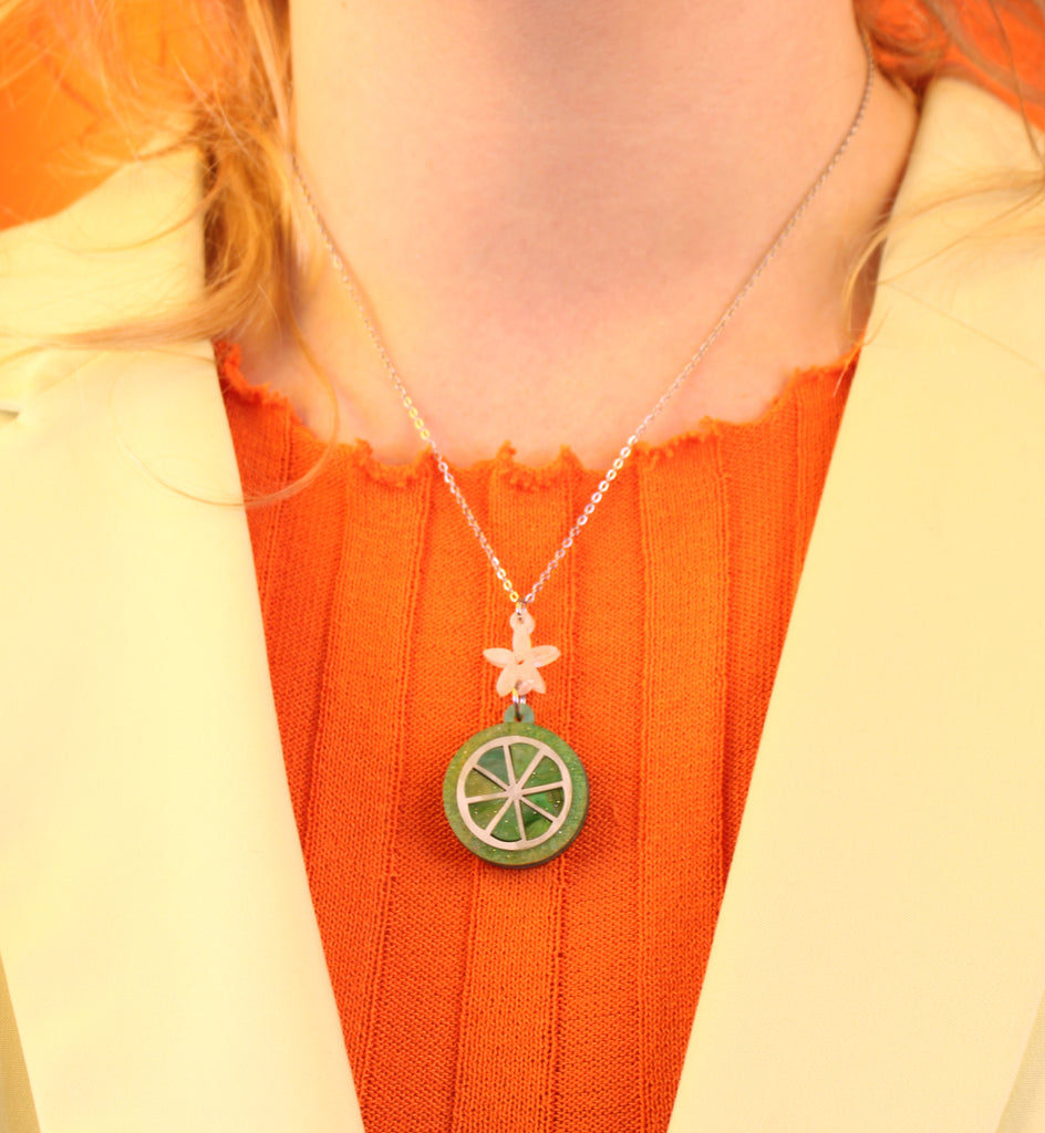 Model wearing Lime slice pendant suspended rom a white flower and stainless steel chain