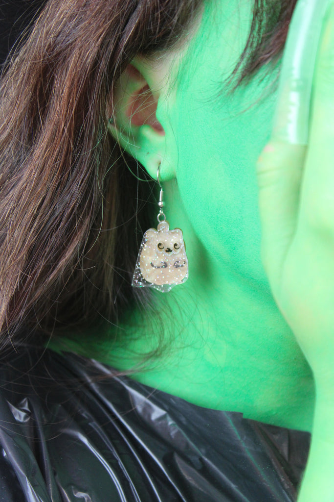 Model wearing hamster charms with a layer of holographic glitter to replicate a ghost on stainless steel earwires