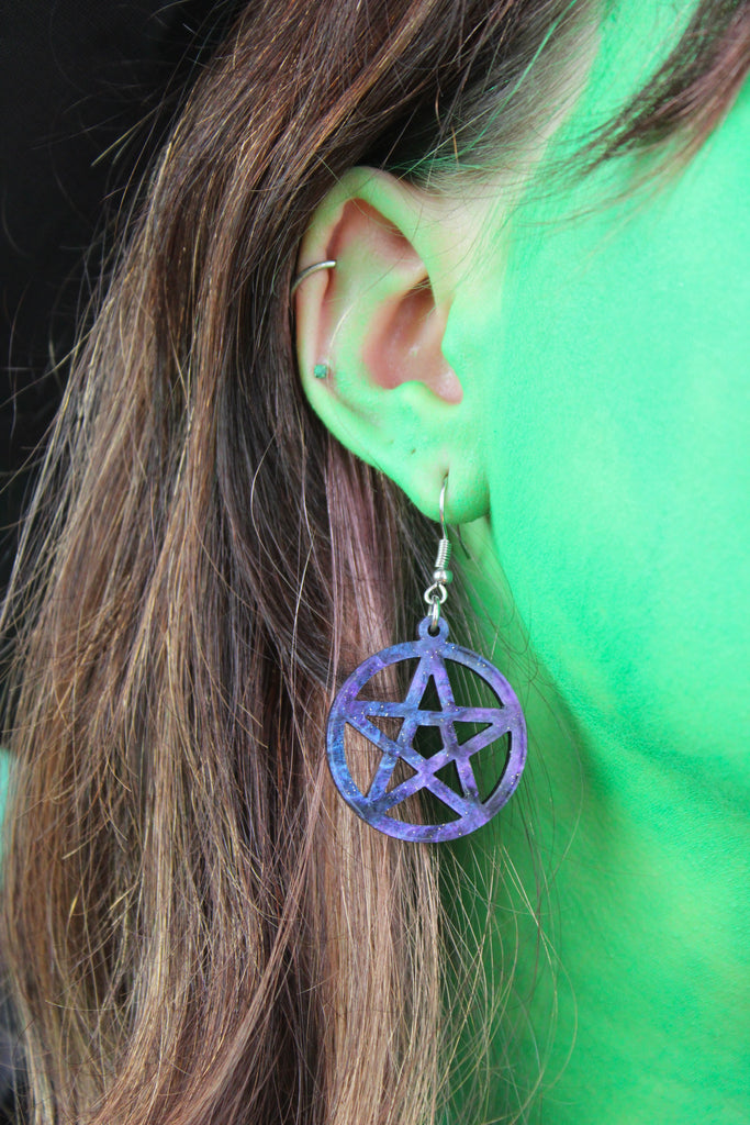 model wearing galaxy-inspired marble pentacle charms on stainless steel earwires