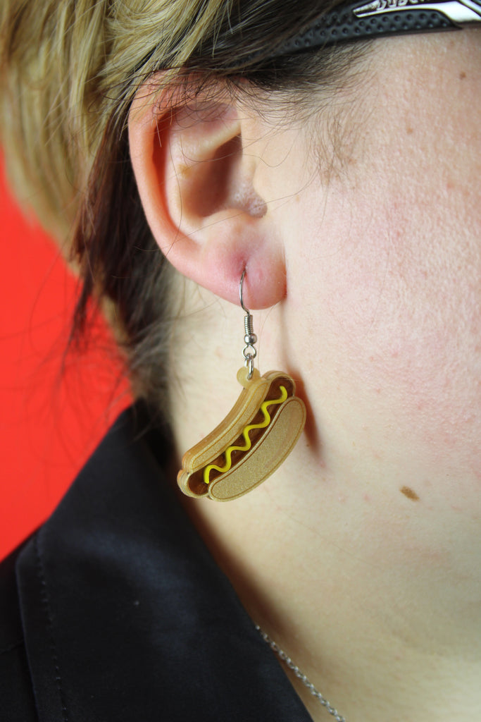 Model wearing mustard hot dog charm on stainless steel earwires