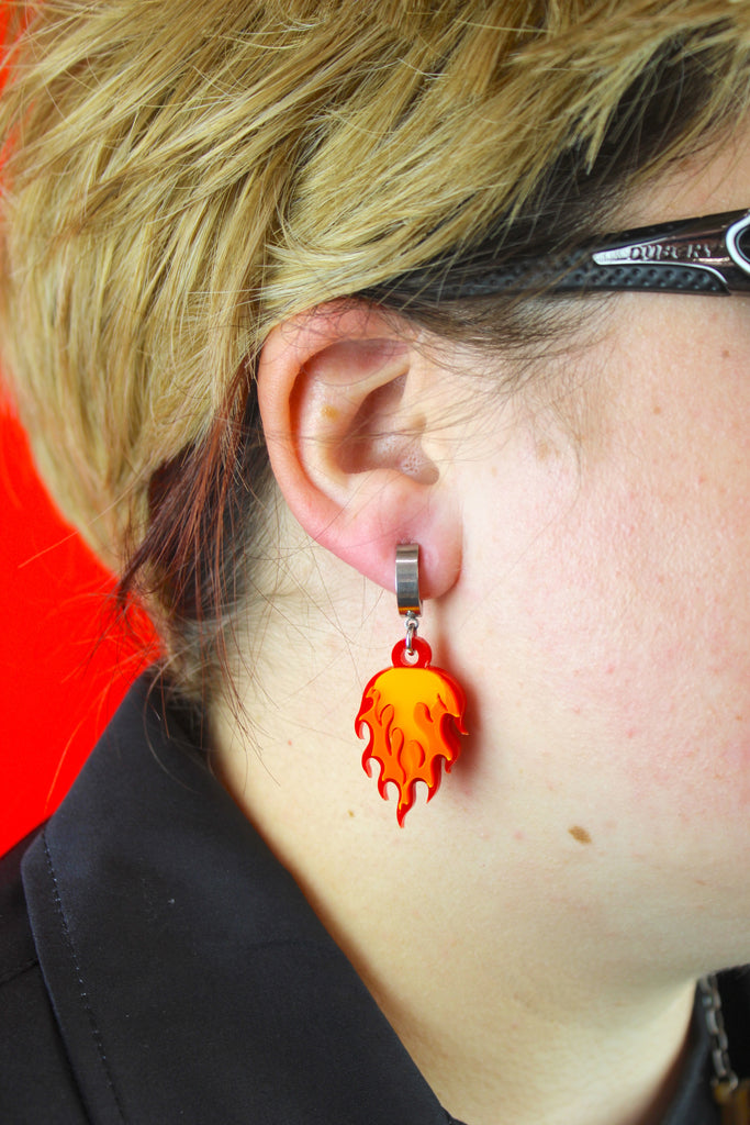 Model wearing Flame charms on stainless steel huggie hoop earrings