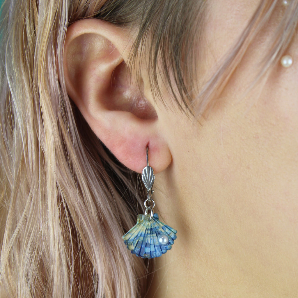 Model wearing Blue abalone shell charms with a faux pearl on stainless steel hoops