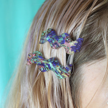 Model wearing Wavy alligator clips featuring a purple abalone design