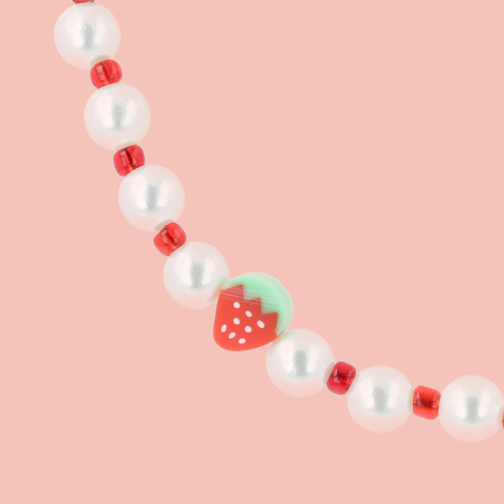 Faux pearl necklace featuring red beads and strawberry charms with a base metal clasp