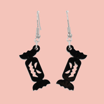 Black sweet wrapper charms with carved out faces on stainless steel earwires