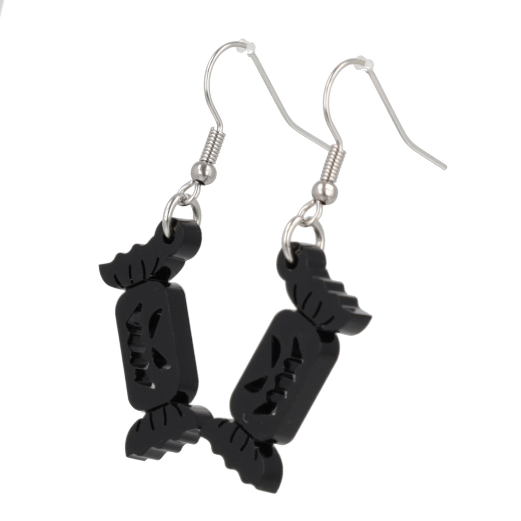 Black sweet wrapper charms with carved out faces on stainless steel earwires