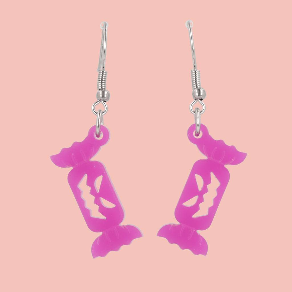 purple sweet wrapper charms with craved out faces on stainless steel earwires