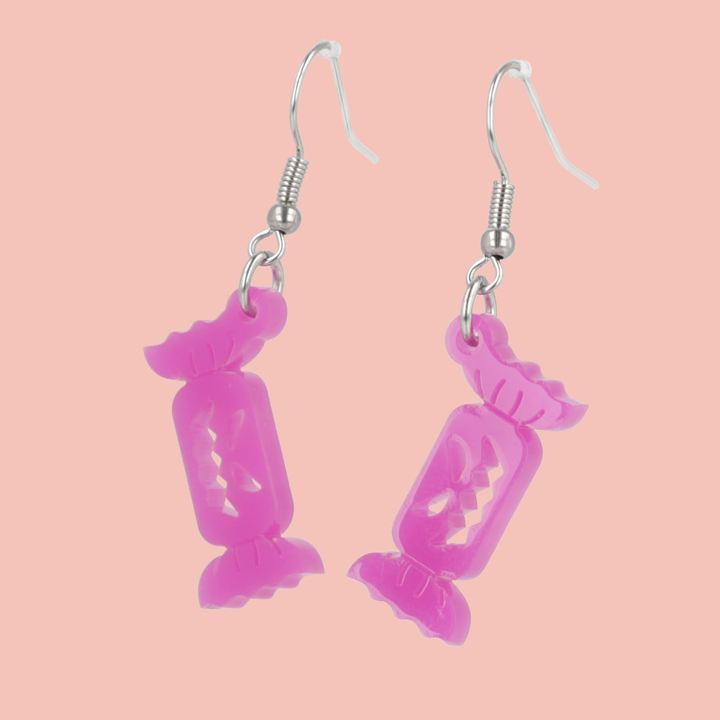 purple sweet wrapper charms with craved out faces on stainless steel earwires