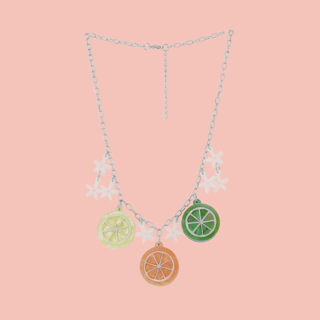 necklace featuring lemon, orange and lime slice pendants and white flowers on an oval link stainless steel chain