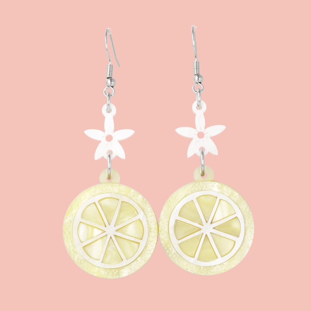 Lemon slice charms suspended fromn white flower charms on stainless steel earwires