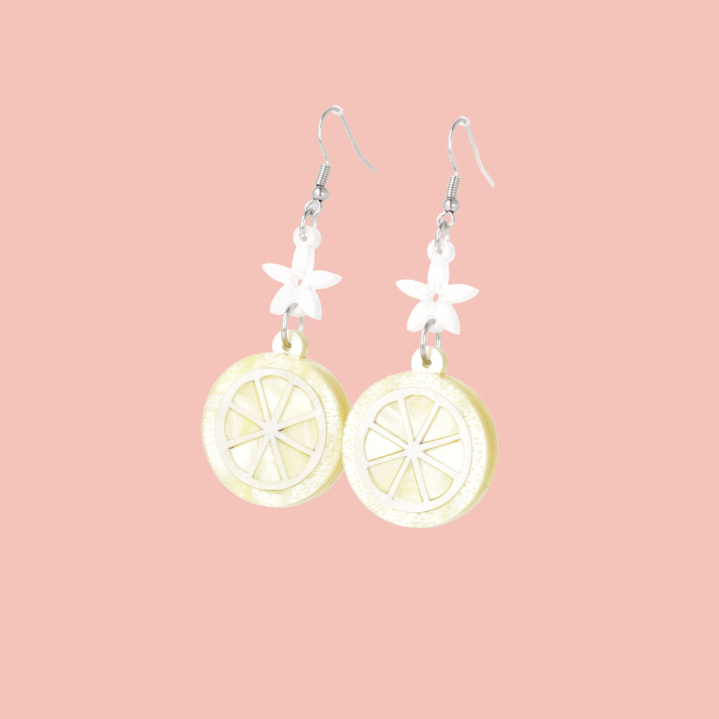 Lemon slice charms suspended fromn white flower charms on stainless steel earwires