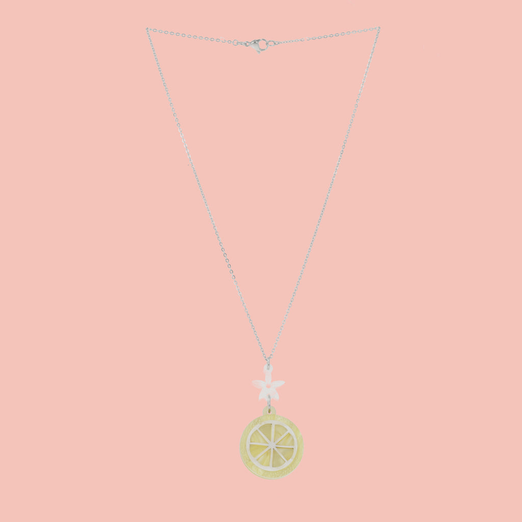 lemon slice pendant suspended from a white flower charm on a stainless steel chain