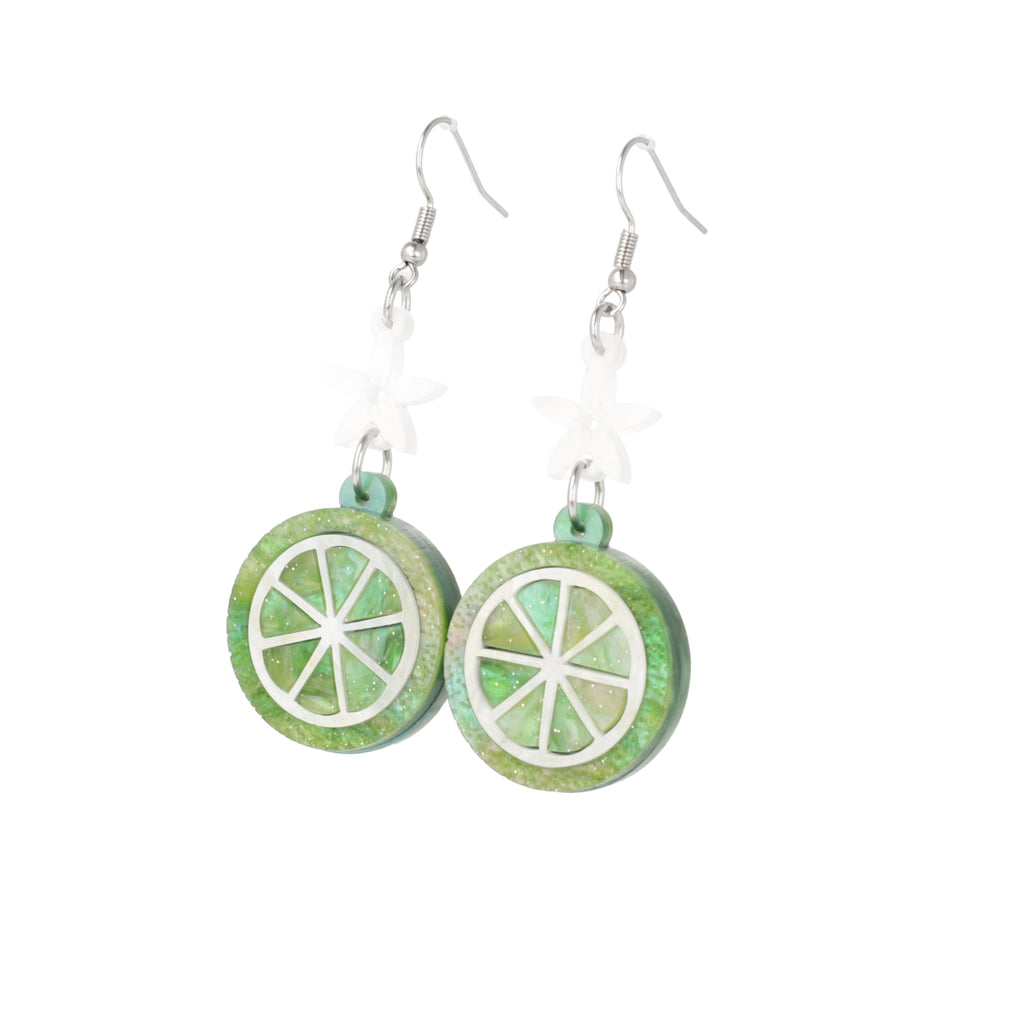 Glittery lime fruit slice charm suspended from a white flower on stainless steel earwires