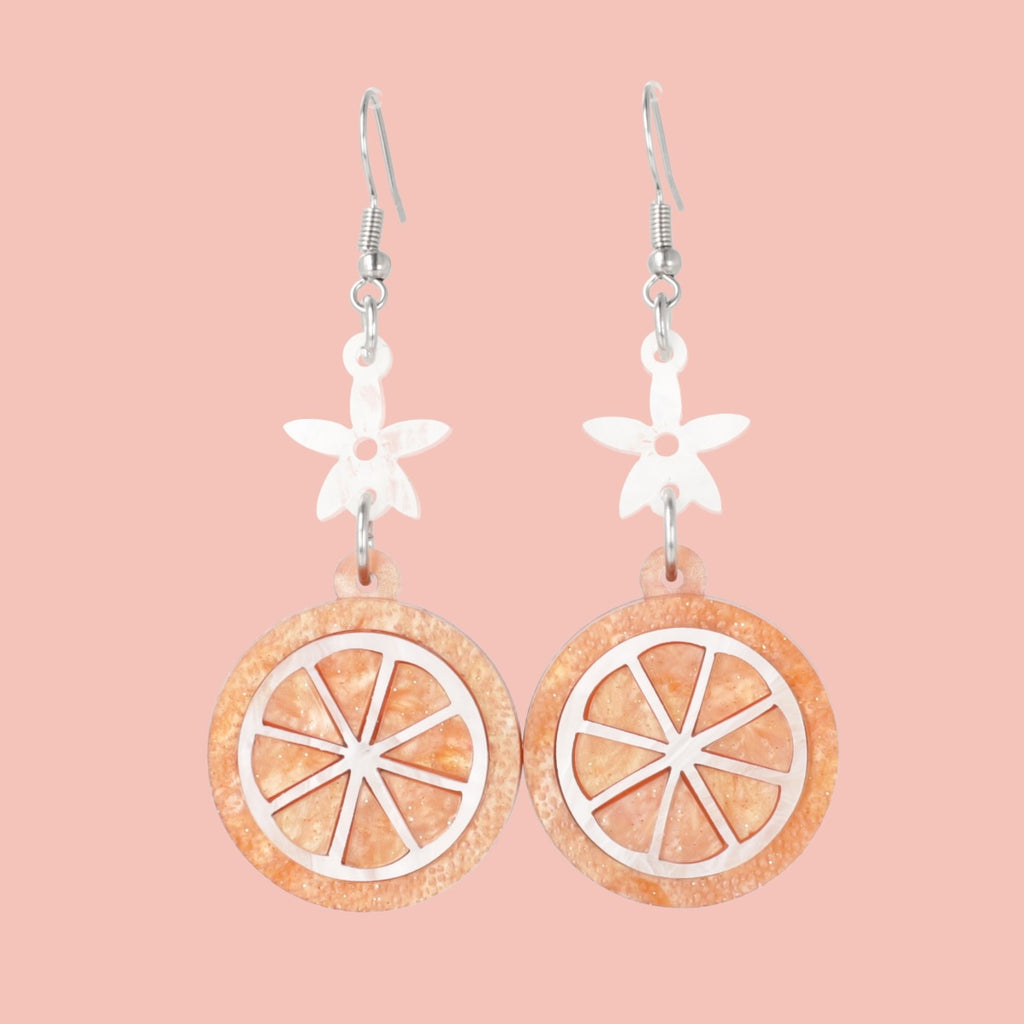 orange slice pendant suspended from white flower charms on stainless steel earwires