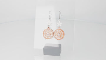 360 view of orange slice pendant suspended from white flower charms on stainless steel earwires