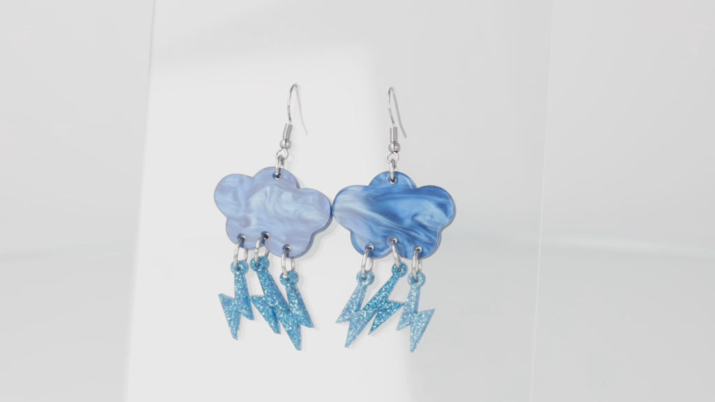 Blue marble clouds attached to blue glitter lightning bolt charms on stainless steel earwires